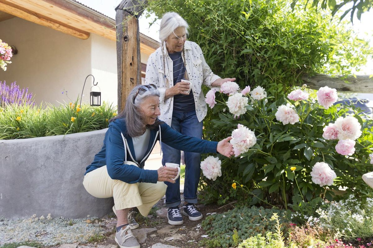 Two women admiring pink flowers in a garden
